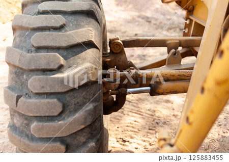 Ground-level view of heavy machinery action in industrial construction environment close-up focus Ground-level view of heavy machinery action in industrial construction environment close-up focus 125883455