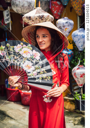 happy beautiful tourist woman in Vietnamese cone hat Non La with fan in Hoi An in Vietnam in Asia happy beautiful tourist woman in Vietnamese cone hat Non La with fan in Hoi An in Vietnam in Asia 125884018