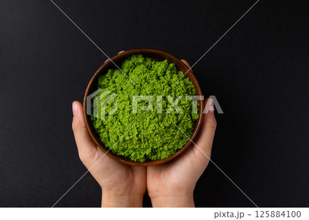 Wolffia or watermeal in bowl with hand on black background Wolffia or watermeal in bowl with hand on black background 125884100