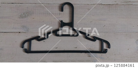 Black plastic hanger flat lay on rustic white wooden background [with room for copy] 125884161