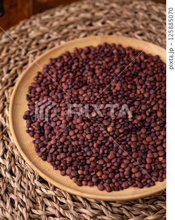 Organic uncooked seeds dark red brown lentils. 125885070