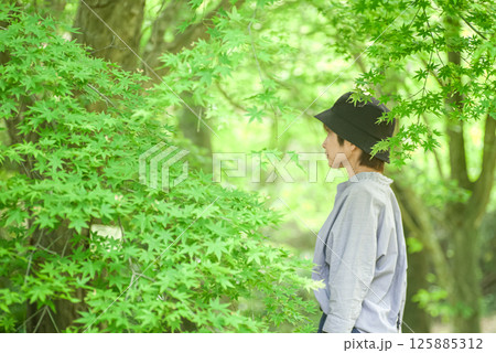 ＜素材＞春先の青いモミジの葉と女性 125885312