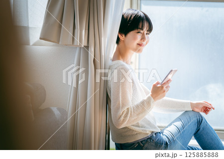 部屋でスマホを操作する女性 部屋でスマホを操作する女性 125885888