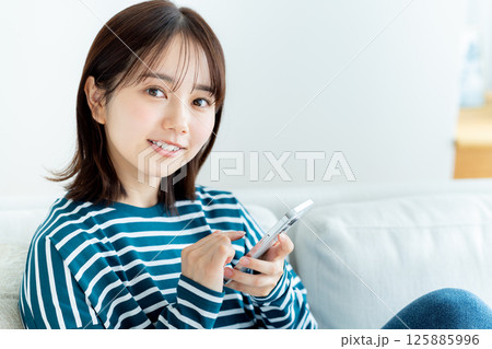 部屋でスマホを操作する若い女性 部屋でスマホを操作する若い女性 125885996