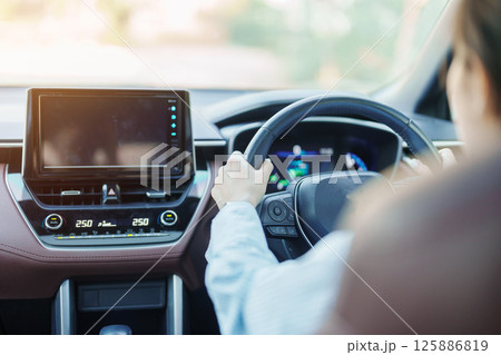 Businesswoman driver driving a car on the road, hand controlling steering wheel in electric modern automobile. Journey, trip and safety Transportation concepts 125886819