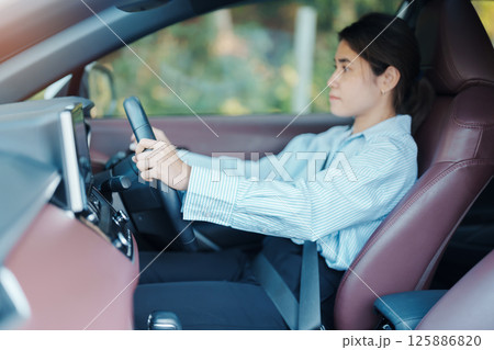 Businesswoman driver driving a car on the road, hand controlling steering wheel in electric modern automobile. Journey, trip and safety Transportation concepts Businesswoman driver driving a car on the road, hand controlling steering wheel in electric modern automobile. Journey, trip and safety Transportation concepts 125886820