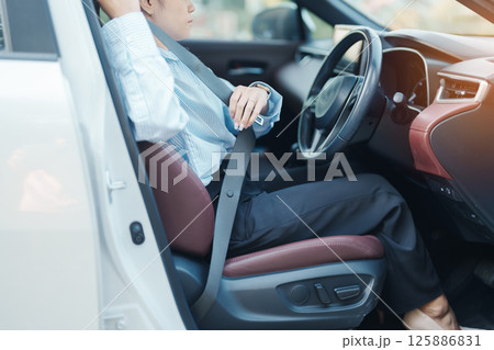 Business woman driver hand fastening seat belt during sitting inside a car and driving in the road. safety, trip, journey and transport concept 125886831