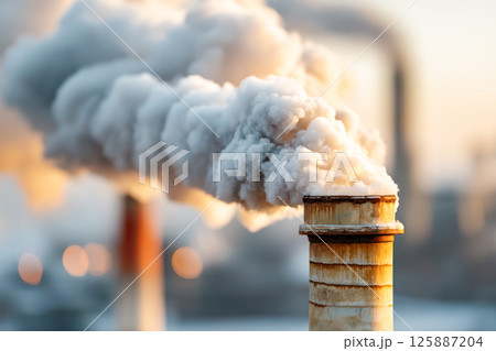Industrial smokestack emitting thick white smoke into the air with modern city buildings in background for pollution and environmental impact concept. 125887204