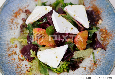 beetroot salad with blue cheese, arugula and walnut in a white plate on gray background, top view 125887466