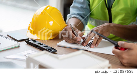 Green tech safety practices with engineers writing in notebook Green tech safety practices with engineers writing in notebook 125887659