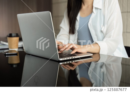 Business professional working on a laptop, focusing on financial tasks in a modern office setting. 125887677