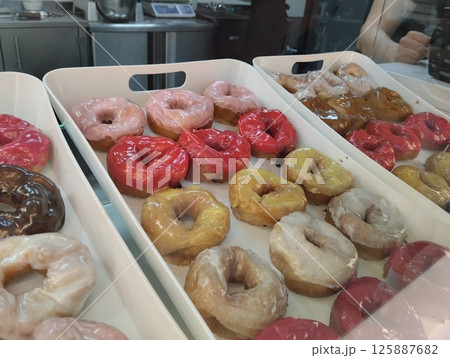 Donuts in a tray with colored glaze and sprinkled with chocolate nuts. National Sweetness Donuts in a tray with colored glaze and sprinkled with chocolate nuts. National Sweetness 125887682