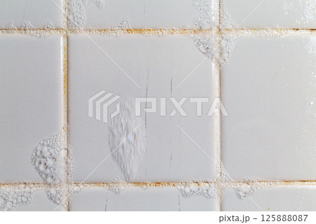 お風呂のタイルの溝に付いたカビを泡で掃除している。 125888087