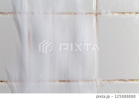 お風呂のタイルの溝に付いたカビを泡で掃除している。 お風呂のタイルの溝に付いたカビを泡で掃除している。 125888088