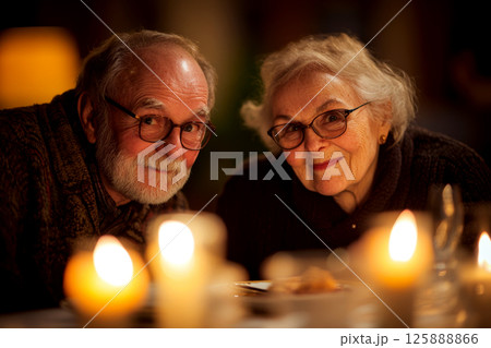 Elderly couple smiling at a candlelit table, displaying warmth and affection. Concept of warmth, love, happiness. For family photo themes. 125888866