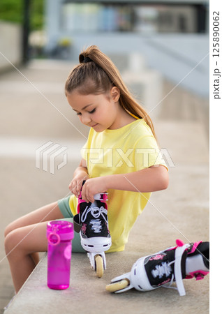 Little girl with roller-skates playing outside Little girl with roller-skates playing outside 125890062