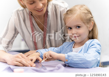 Mom and daughter cutting out anew model and looking involved Mom and daughter cutting out anew model and looking involved 125890143