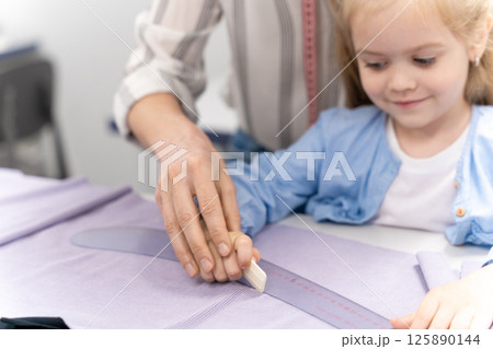 Mom and daughter cutting out anew model and looking involved 125890144