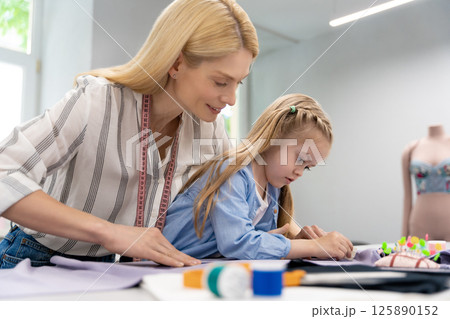 Mom and kid working on a new model in a design studio Mom and kid working on a new model in a design studio 125890152