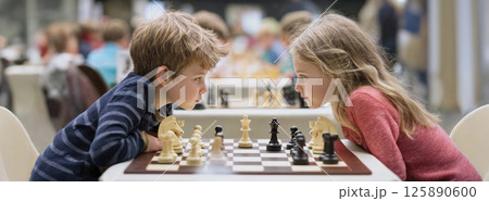 Chess tournament. Boy and girl competitors are looking at each other intensely 125890600