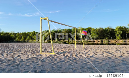 A colorful ball flies into an empty gate on the beach. playing ball on the beach. Fun outdoor activities. kid dreams. 125891054