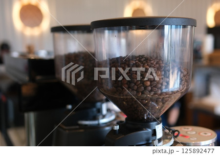 Coffee beans are placed next to a manual grinder. 125892477