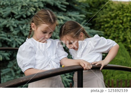 Twin girls study the snail crawling nearby. Sweet twin girls. 125892539