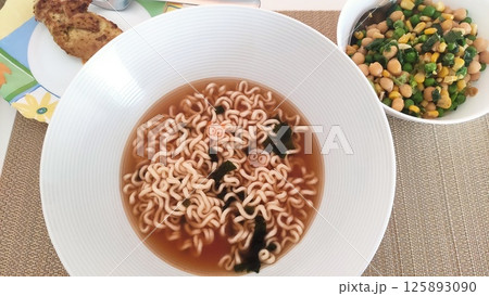 Bowl of instant noodles with narutomaki and side dish on placemat Bowl of instant noodles with narutomaki and side dish on placemat 125893090
