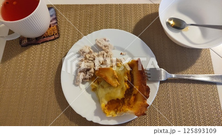 Savory pie and shredded chicken breast on white plate, enjoying a healthy meal Savory pie and shredded chicken breast on white plate, enjoying a healthy meal 125893109