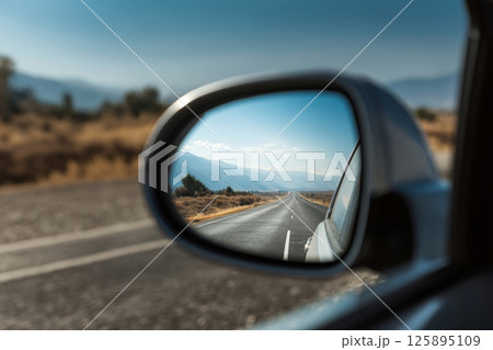 Scenic road in rearview mirror during road trip 125895109