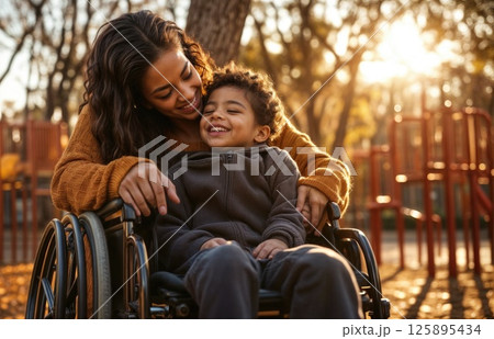Hispanic mother and child bonding outdoors in wheelchair amidst autumn sunlight 125895434