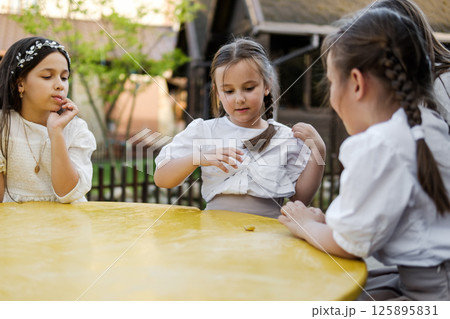 The girls are sitting at a bright yellow children's table in a cozy corner.  125895831