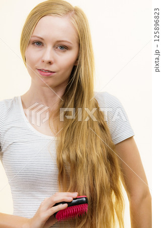 Blonde girl brushing her long hair Blonde girl brushing her long hair 125896823
