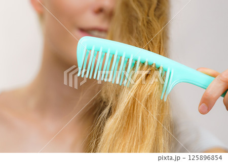 Blonde girl combing her long messy hair Blonde girl combing her long messy hair 125896854