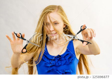 Young woman with scissors for haircutting Young woman with scissors for haircutting 125896877