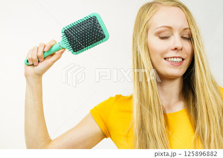 Blonde girl brushing her long hair 125896882