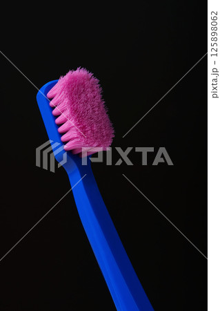 Used plastic toothbrush with pink bristles on black background. Germs. Time to throw it away and replace it with a new one. 125898062