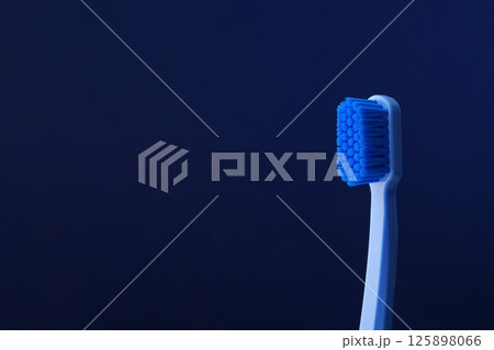 Close-up of a blue plastic toothbrush on a blue background. Space for text. Dentistry. Close-up of a blue plastic toothbrush on a blue background. Space for text. Dentistry. 125898066