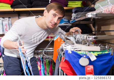 Young man shopping for swimwear in clothing store 125898172
