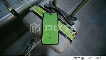 Airport Terminal: Mobile Phone with Green Chroma Key Display Mock Up Lying on Suitcase 125898248