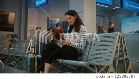 Airport Terminal: Happy Woman with Suitcase Sitting in Boarding Lounge After Security Check, 125898307