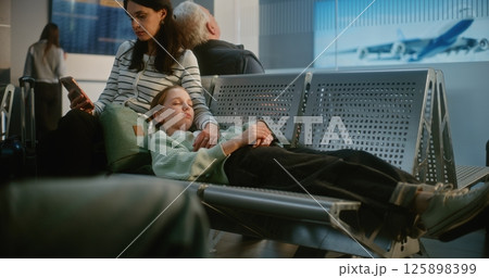 Tired Teen Girl Sleeping on Seats, Woman Scrolling Phone in Boarding Lounge of Airline Hub Tired Teen Girl Sleeping on Seats, Woman Scrolling Phone in Boarding Lounge of Airline Hub 125898399