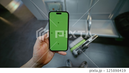 Airport Terminal: POV Man Holding Mobile Phone with Green Chroma Key Display. First-Person View Airport Terminal: POV Man Holding Mobile Phone with Green Chroma Key Display. First-Person View 125898419