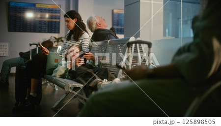 Mother and Daughter in Crowded Airport Terminal: Exhausted Teenage Girl Lying on Seats 125898505