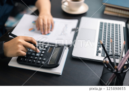 Finance bank tax expense accounting budget money businessman hand use calculator Financial calculate accountant close up calculator with graph chart write office desk Business expense analysis saving 125898655