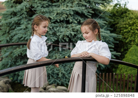 The twin girls are watching the snail's movement with interest. The twin girls are watching the snail's movement with interest. 125898848