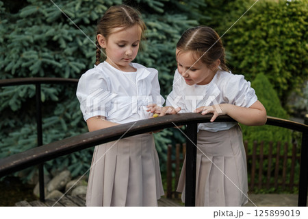 The little twins lean over to a snail crawling on a tree. The little twins lean over to a snail crawling on a tree. 125899019