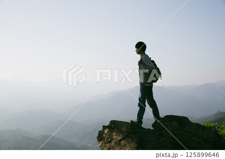 Man traveler with camera backpack hiking outdoor travel lifestyle and adventure concept. cap backpack and join of tourist for green mountain tour, beauty of nature and expansive sky people of tourism Man traveler with camera backpack hiking outdoor travel lifestyle and adventure concept. cap backpack and join of tourist for green mountain tour, beauty of nature and expansive sky people of tourism 125899646