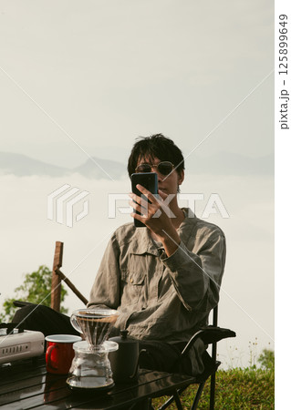 Young business man working computer on peak hill. Hiker online shopping on laptop at sunset, sunrise on top mountain, freelance person remote work with digital tablet. travel vacation holiday concept 125899649
