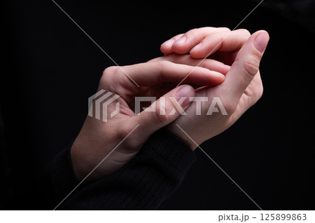 Close-up image of beautiful female hands with delicate pink manicure on nails on black background. Hand skin care, manicure and beauty treatments. Elegant and graceful hands with thin graceful fingers 125899863